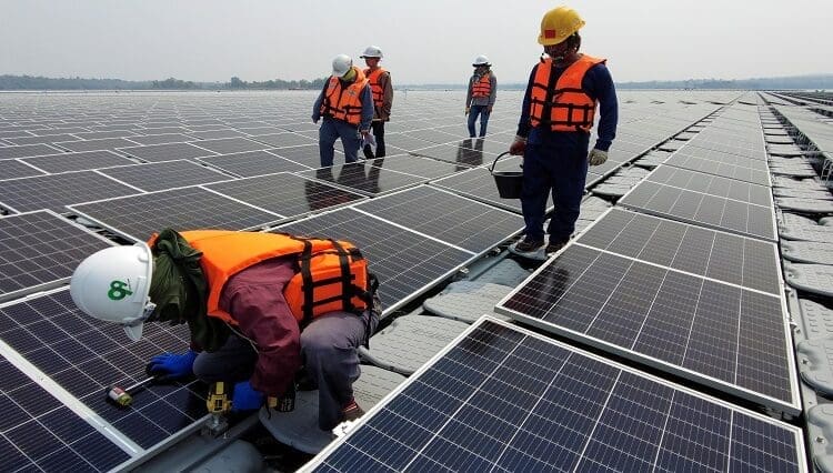 A worker kneels by one of the solar cell panels over the water surface of Sirindhorn Dam in Ubon Ratchathani, Thailand April 8, 2021. Picture taken April 8, 2021 with a drone. REUTERS/Prapan Chankaew