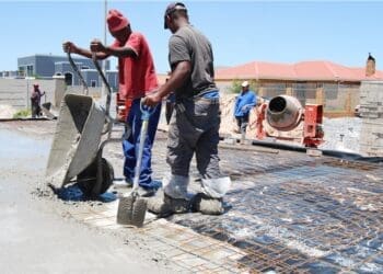 Construction workers pour cement on site, reflecting the labour-intensive building industry where leaders and SMEs are calling for practical regulation that balances compliance requirements with worker protection.
Photo: SANS